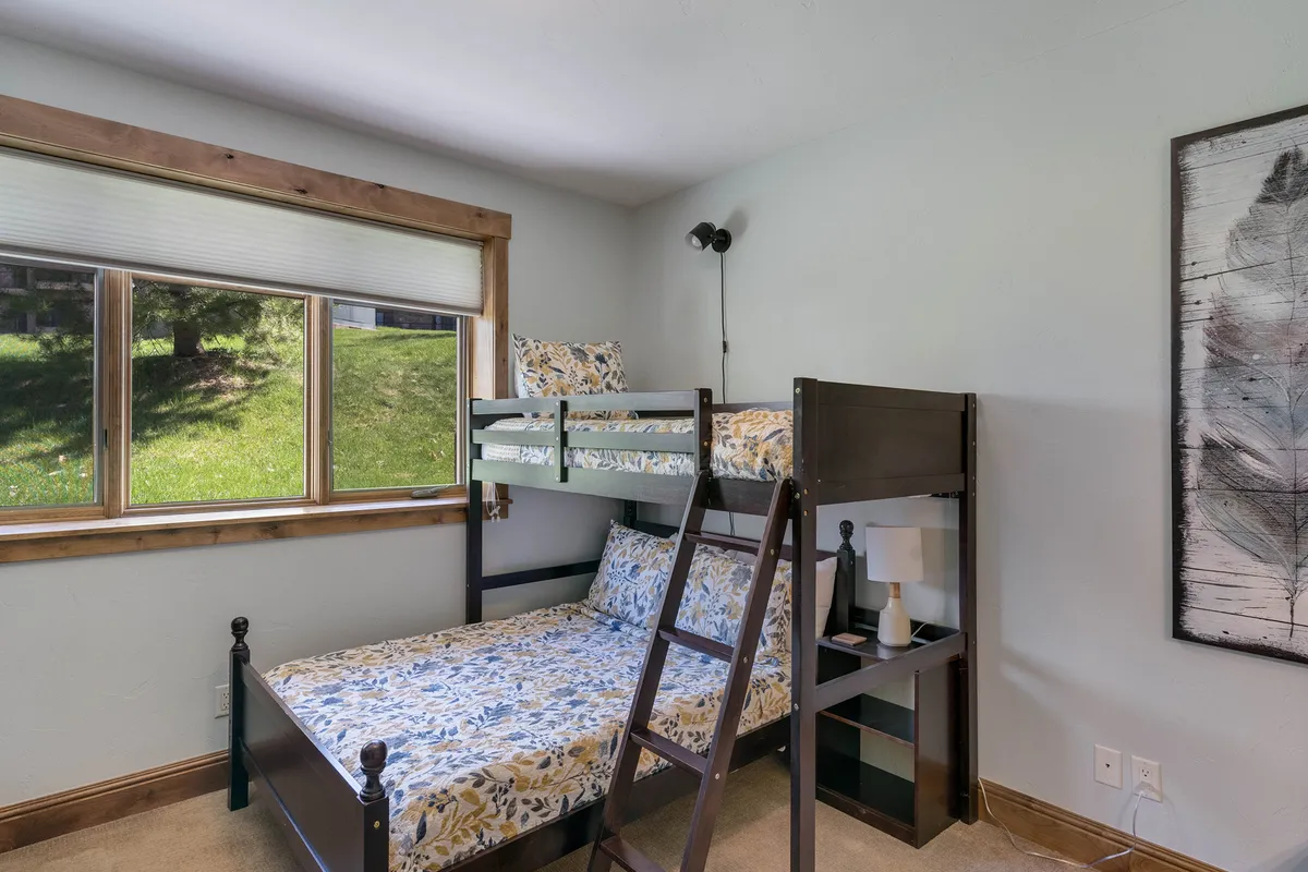 A family-friendly bedroom outfitted with a bunk bed, cheerful bedding, and a bright window view. The decor is playful yet sophisticated, inviting children or groups to settle in. Decorative artwork adds warmth, and the space feels perfect for memorable family sleepovers or group stays.
