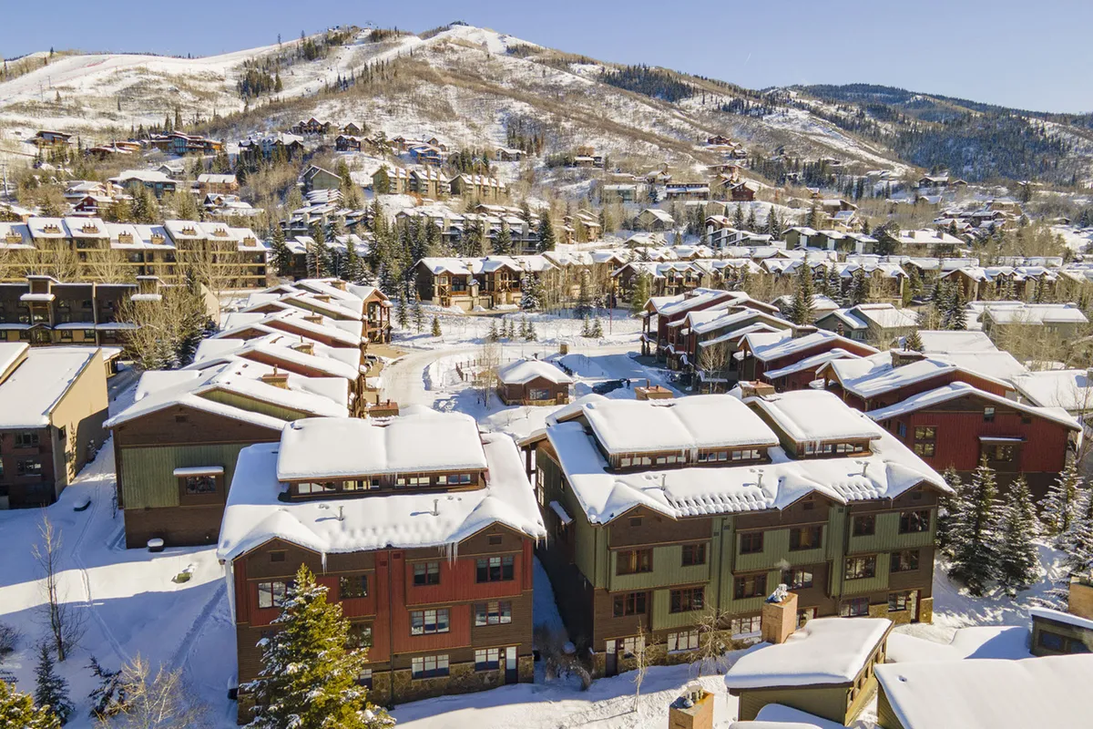 A sweeping view of snow-covered rooftops against a dramatic mountain backdrop, with a tree-lined horizon. The image conveys the natural beauty and tranquility of the surrounding Steamboat area, highlighting the scenic environment that frames the property.