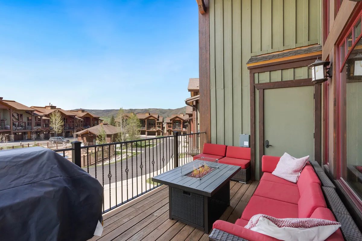 An inviting exterior scene featuring a cozy red-seated fire pit area with panoramic mountain views. The setting is ideal for gathering outdoors after an active day, enjoying sunset vistas or sharing stories by the fire under the open sky.