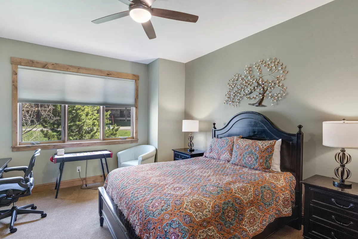 A tranquil bedroom featuring a comfortable bed with patterned bedding, large window streaming in natural light, and tasteful wall art. The space feels airy and inviting—a restful haven for couples or solo travelers to recharge.