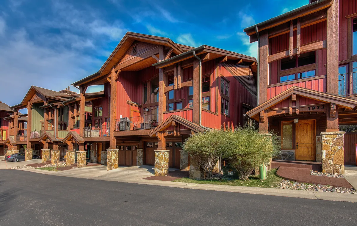 A welcoming exterior shot capturing wooden architecture, stone accents, and colorful facades. The image hints at outdoor gatherings, the charm of the neighborhood, and easy access to local events or nature.