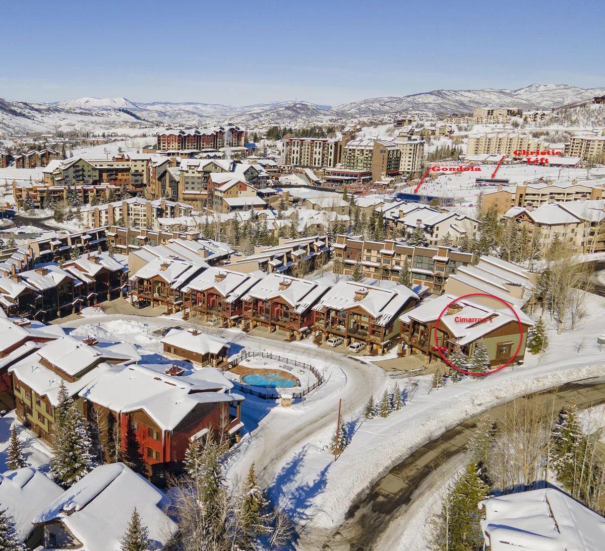 This exterior image captures snow-covered rooftops with the surrounding mountains and features the nearby gondola station. The outdoor pool is also visible, highlighting both the convenience of the location for ski access and the après-ski relaxation amenities. The overall scene is cheerful and adventurous, evoking the excitement of a ski getaway.